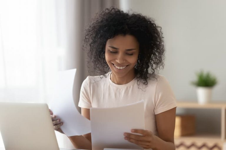 Eine Frau lächelt über ihr qualifiziertes Arbeitszeugnis in der Hand