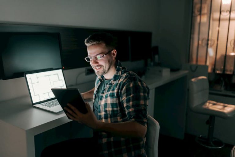 Ein Mann sitzt abends im Büro und ist zufrieden da er nach Vertrauensarbeitszeit arbeiten kann