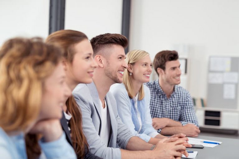 Mehrere Frauen und Männer sitzen am Tisch im Assessment Center