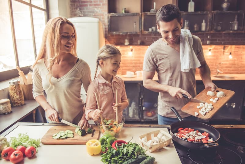 Bei einer 4-Tage-Woche bleibt mehr Zeit für die Familie, ein Mann kocht mit Frau und Kind