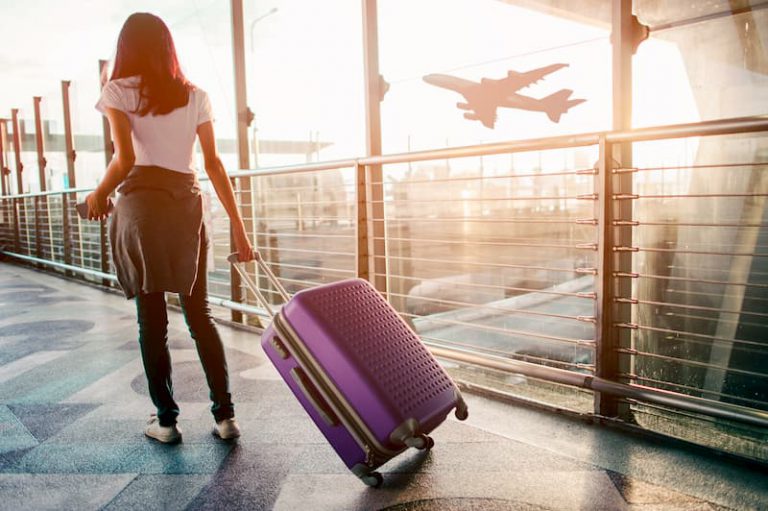 Eine Frau ist mit dem Koffer am Flughafen