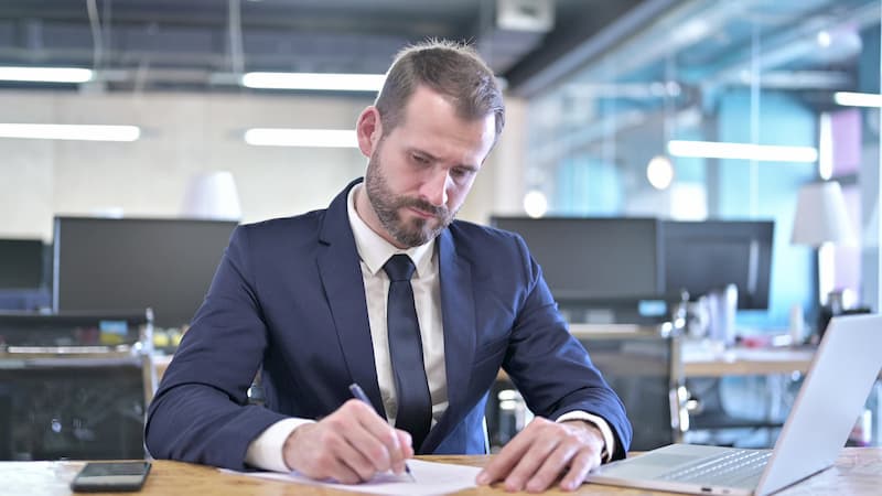 Ein skeptischer Arbeitnehmer unterschreibt einen befristeten Arbeitsvertrag