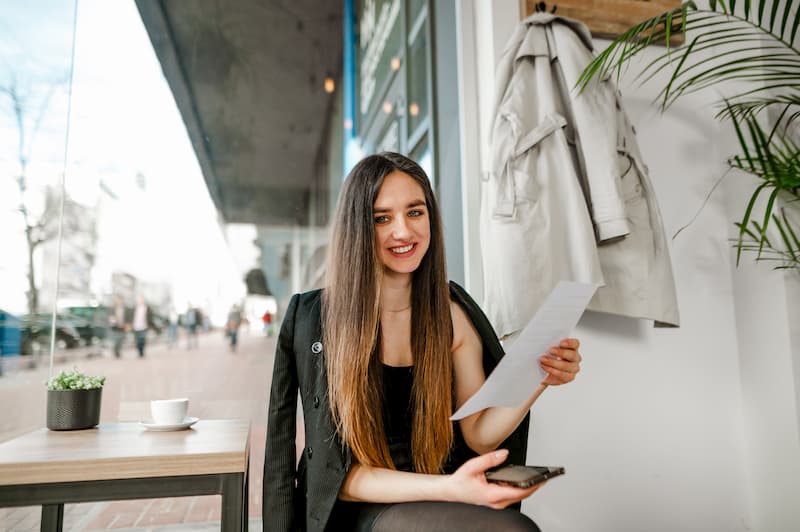 Eine Frau lächelt, da sie einen Ausbildungsvertrag in der Hand hält