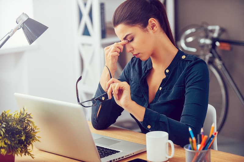 EIne Frau ist müde am Arbeitsplatz, eine Reaktion auf Stress