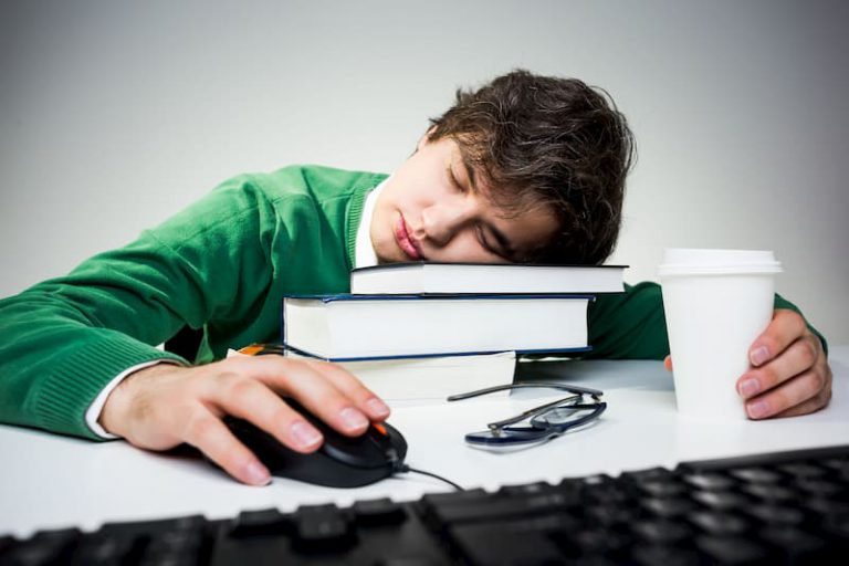 Ein Mann leidet an Boreout und ist übermüdet auf der Arbeit, deswegen schläft er auf Büchern