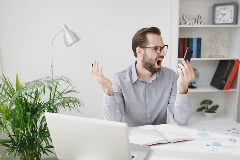 Ein Mann nutzt sein Handy am Arbeitsplatz, dies kann zu den Kündigungsgründen gehören