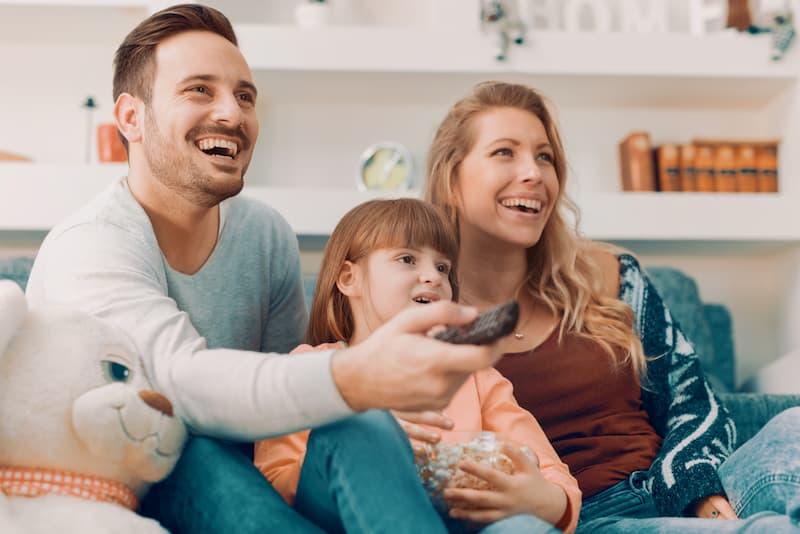 Zwei Eltern mit ihrem Kind auf dem Sofa, sie gehören in eine eigene Steuerklasse