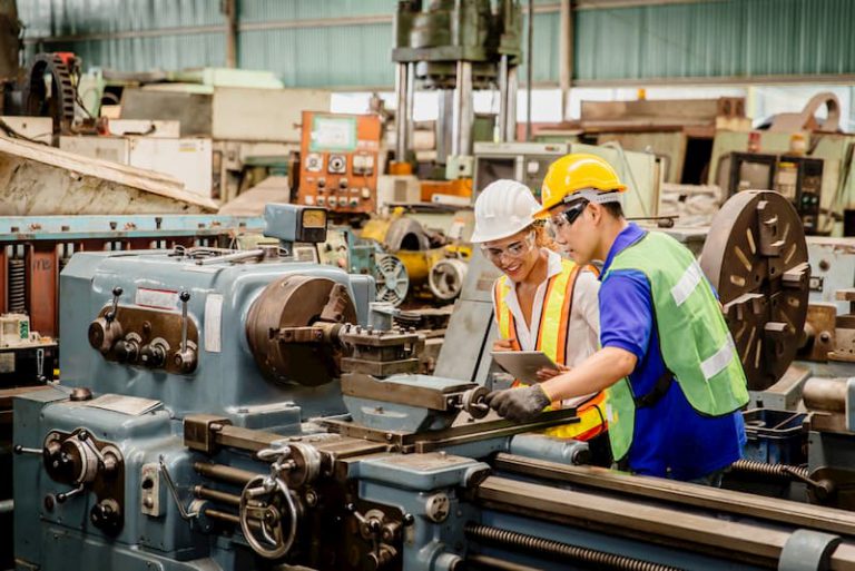 Eine Industriearbeiterin bekommt Hilfe vom Kollegen bei der Wiedereingliederung in den Job