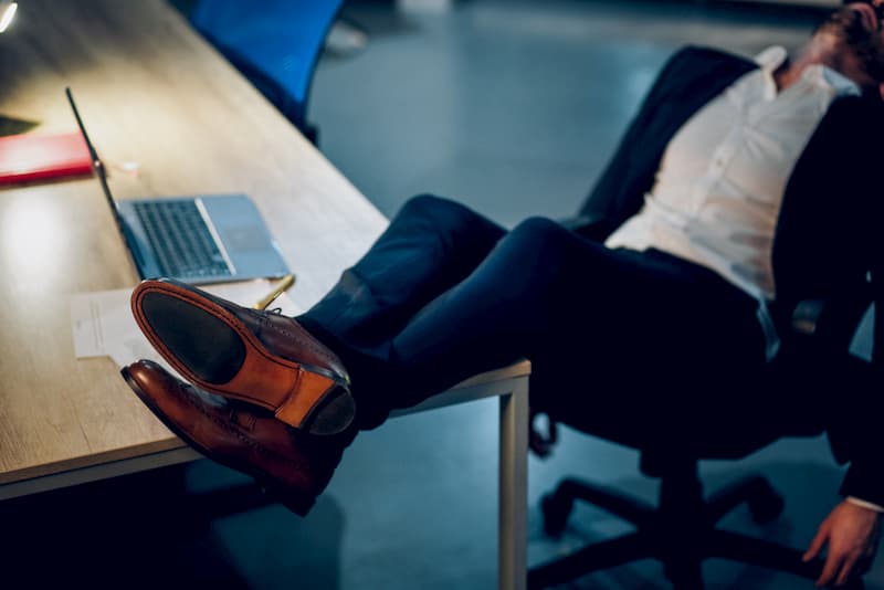 Ein Mann legt bei der Arbeit die Füße auf den Tisch, eine mögliche Form von Arbeitsverweigerung