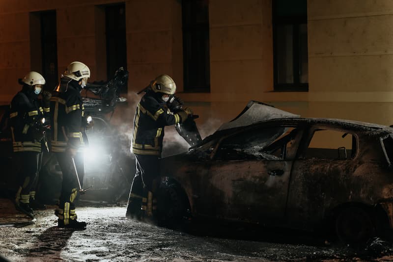 Feuerwehrmänner bei der Nachtarbeit, sie löschen ein Auto