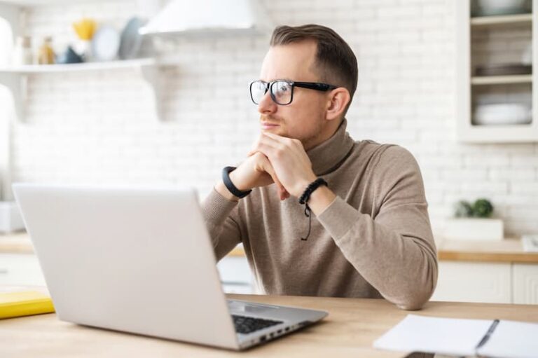 Ein Mann sitzt am Laptop und ist nachdenklich nach einigen Bewerbungs- und Job-Absagen