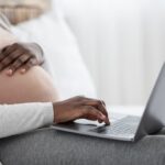 Eine schwangere Frau mit Notebook möchte sich bewerben