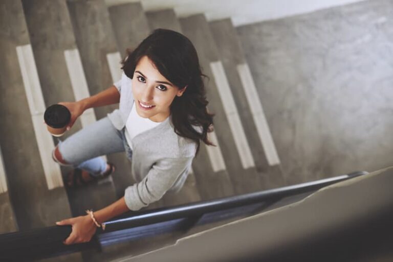 Eine Frau geht eine Treppe hinauf, wie gelingt der Wiedereinstieg nach der Elternzeit?