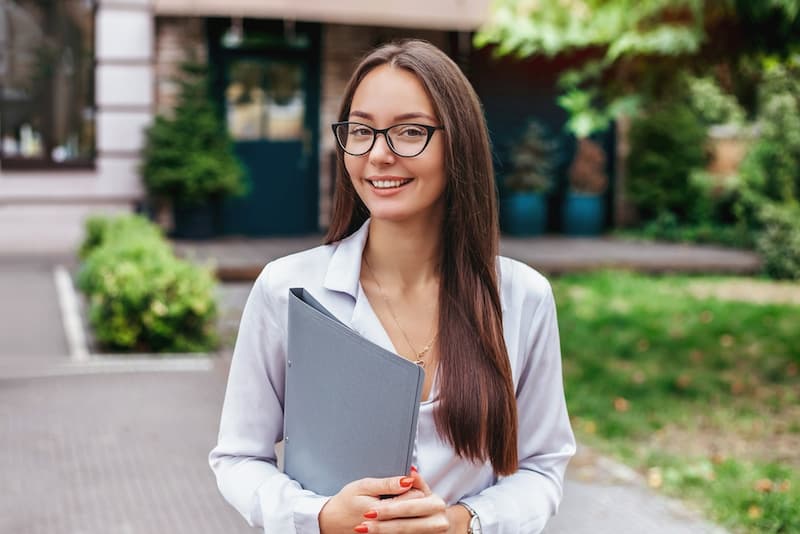 Eine junge Frau mit einem Ordner in der Hand, wie gelingt der Ausbildungsbeginn?