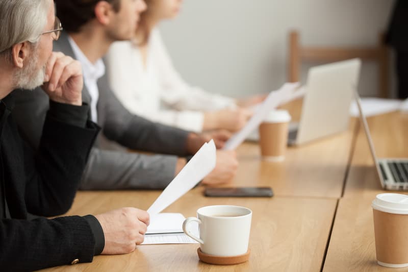 Mehrere Menschen halten bei einem Meeting die Agenda in der Hand