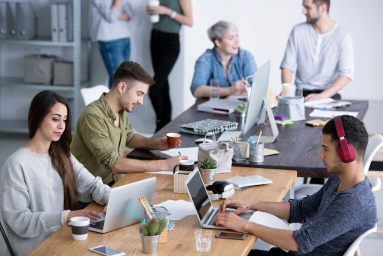 Menschen sitzen im Büro am Tisch, was ist eine gute Arbeitsatmosphäre?