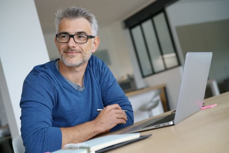 Ein Mann sitzt zufrieden am Laptop, er ist in Frührente