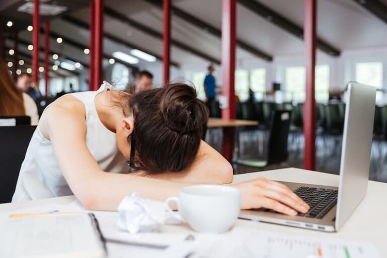 Eine Frau im Büro, ihr Kopf liegt auf den Armen, denn sie hat keine Motivation zu arbeiten