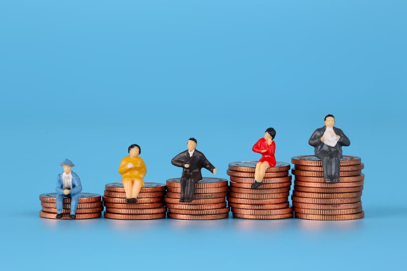 Mehrere Figuren sitzen auf Münzen, welche Vorteile hat Gehaltstransparenz im Beruf?