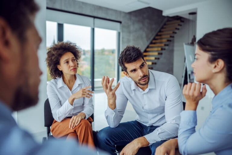 Mehrere Mitarbeiter in einer ernsten Diskussion, was ist Konfliktfähigkeit?