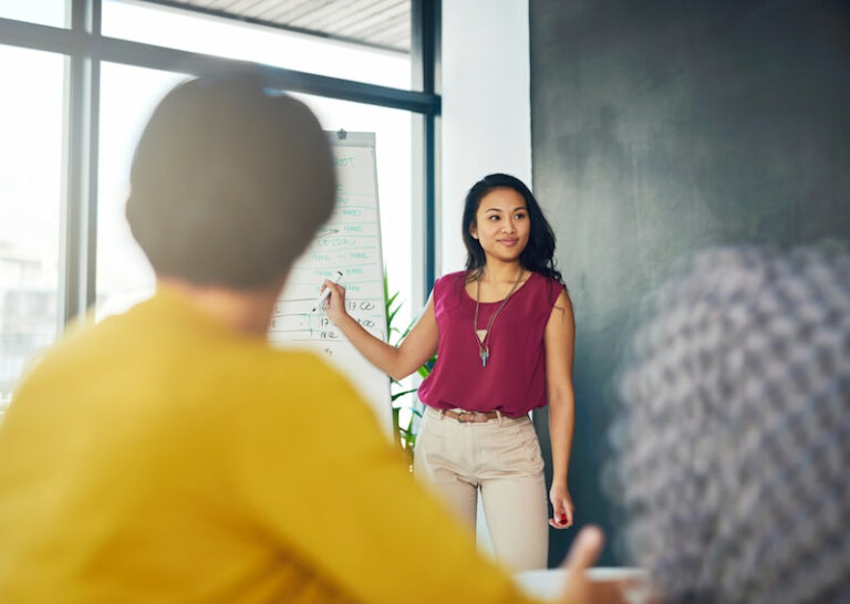 Eine Frau mir gutem Personal Branding hält einen Vortrag. Dafür nutzt sie ein Whiteboard. Sie erklärt "Was ist Personal Branding?"