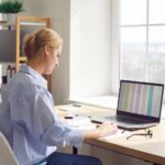 Eine Frau sitzt am Laptop und nutzt digitale Kompetenzen, um eine Tabelle auszuwerten.