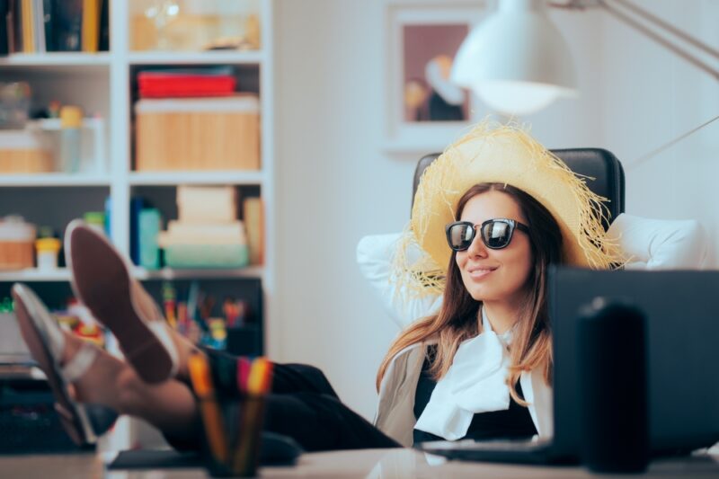 Arbeitnehmerin sitzt in Urlaubskleidung am Schreibtisch