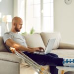 Kranker Mitarbeiter am Laptop nimmt Übergangsgeld in Anspruch