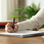 Eine Frau macht sich in einem Block Notizen. Sie geht nach der Cornell-Methode vor.