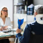 Ein verletzter Mann sitzt vor einer Fachangestellten. Er stellt einen Antrag auf Verletztengeld.