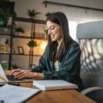 Arbeitnehmerin arbeitet im Homeoffice an ihrem Laptop. Ungewöhnlich: Es handelt sich um ihre erste Tätigkeitsstätte.